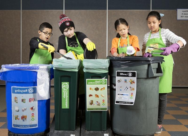 四个小学生把食物垃圾分类到五颜六色的垃圾桶里